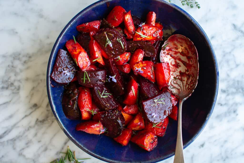 A blue bowl full of roasted beets and carrots. 