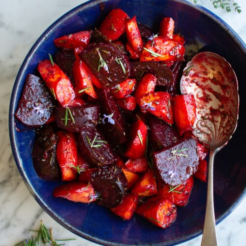 A blue bowl full of roasted beets and carrots.