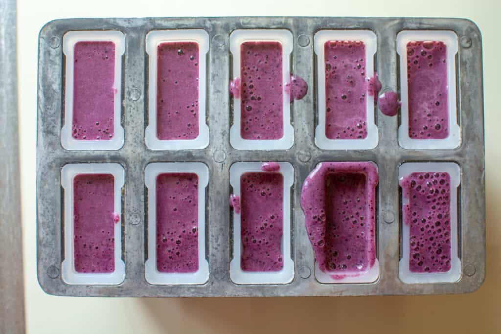 An overhead image of a popsicle mold filled with popsicle filling. 