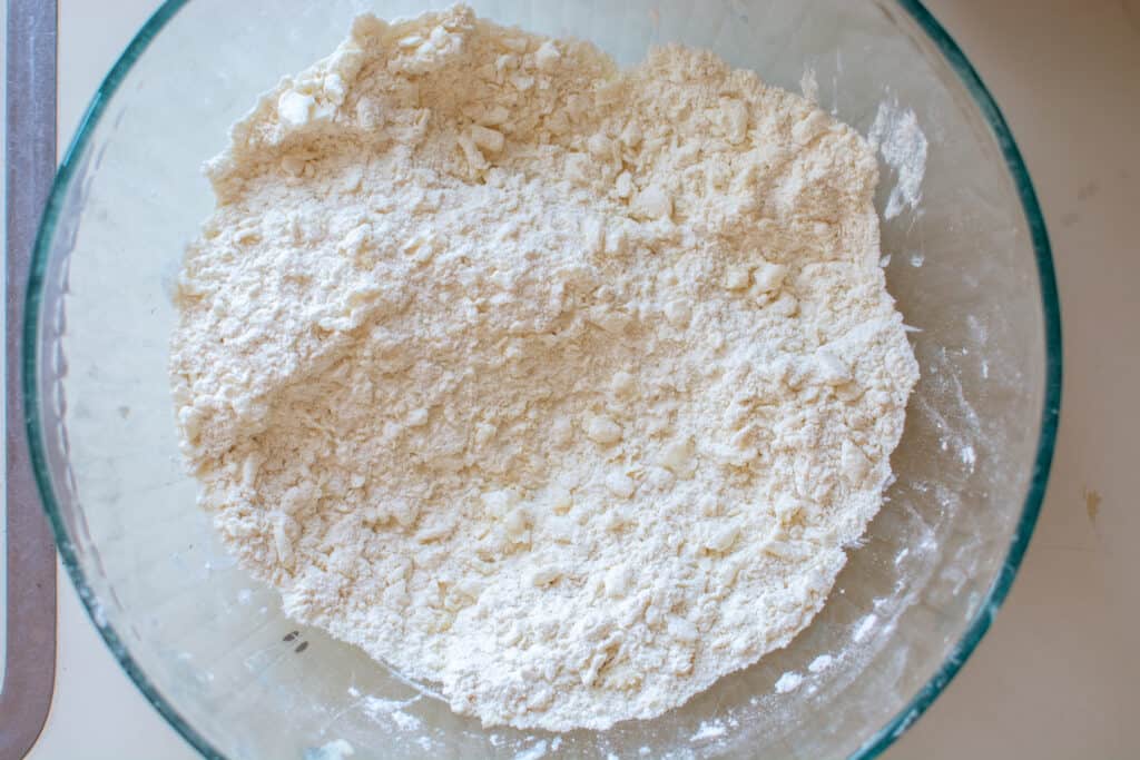 A glass bowl with the flour mixture to make the pie crust and little pieces of fat mixed in. 