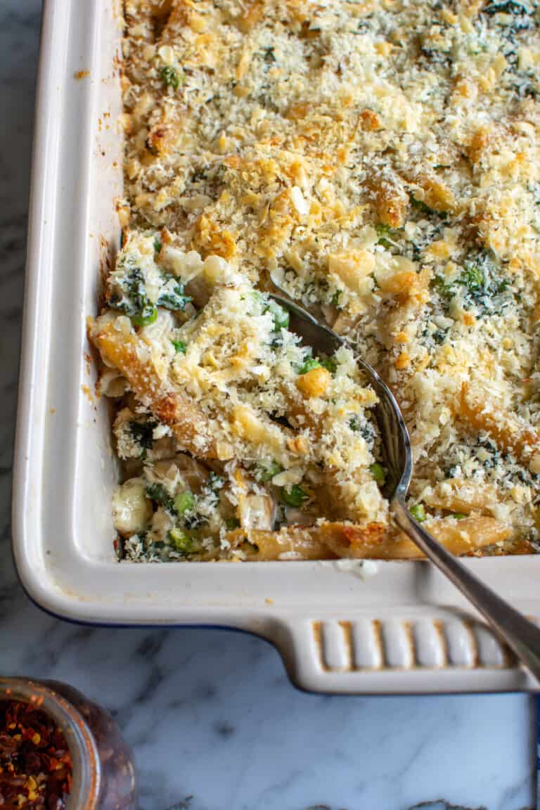 A baking dish filled with chicken noodle casserole with a spoon in. it.