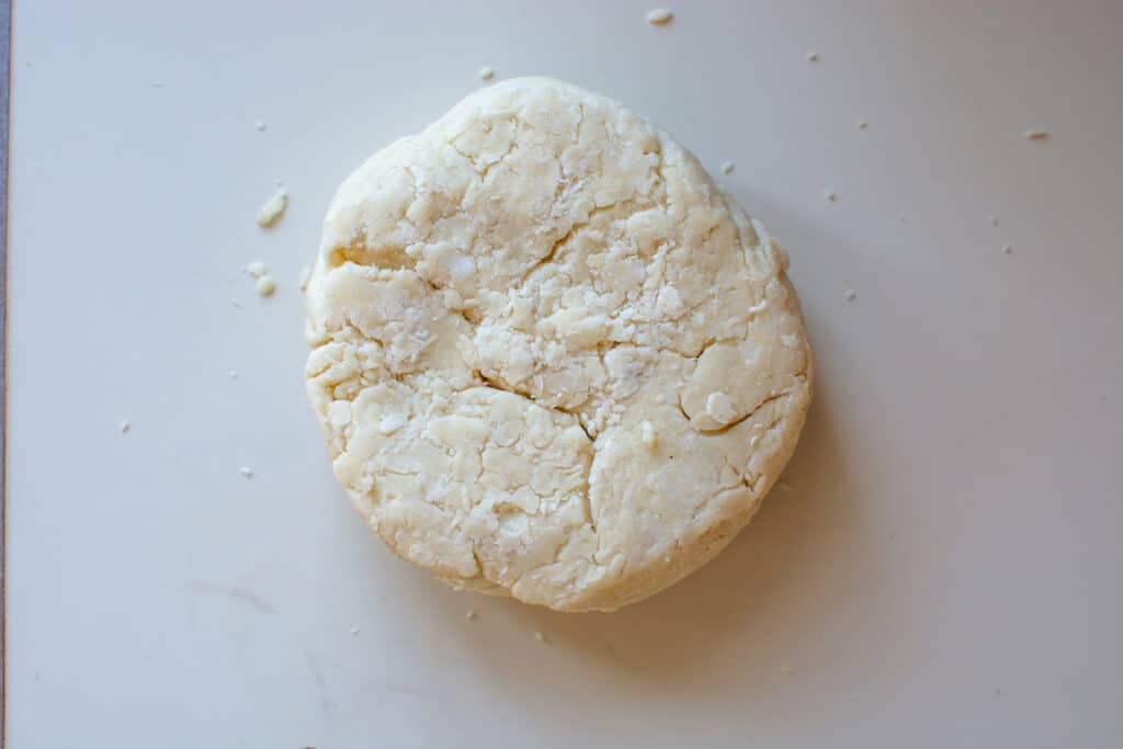 A round of pie dough sitting on a white counter. 