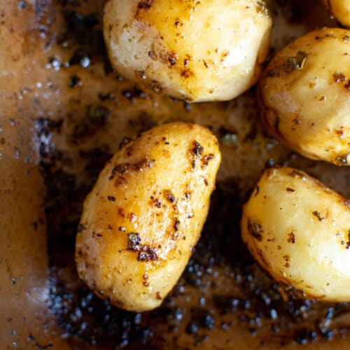 A close-up of roasted baby potatoes in a glass baking dish.