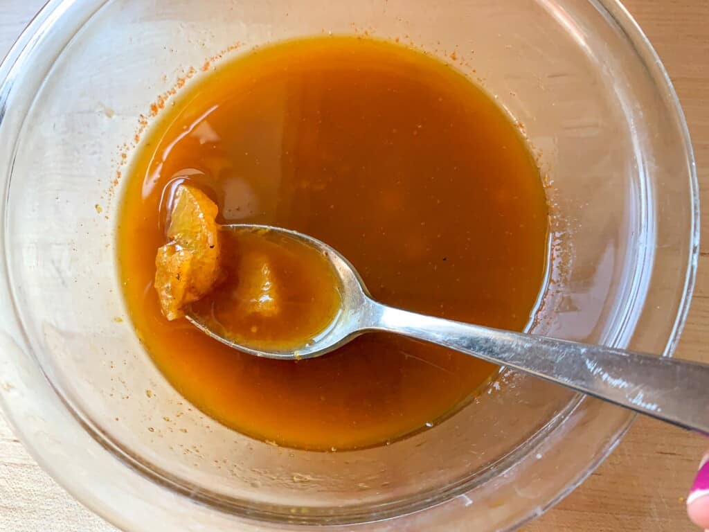 The orange balsamic dressing in a glass bowl. 