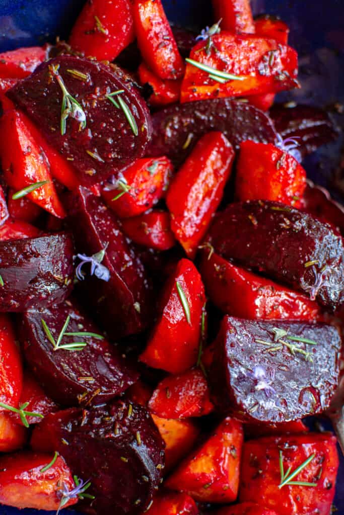 A close up of roasted beets and carrots garnished with rosemary
