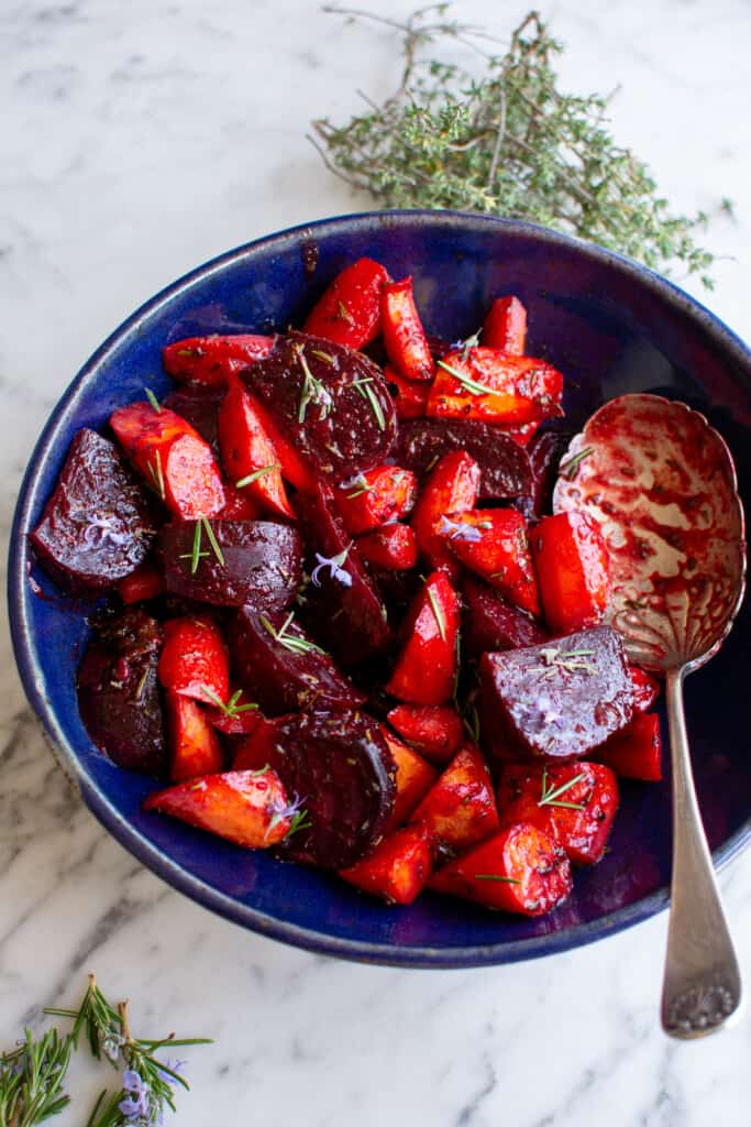 roasted beets and carrots in a blue bowl on a marble table. 