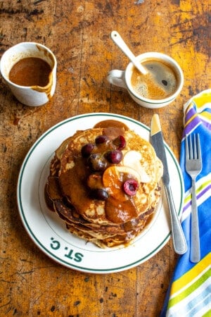 A tall stack of pancakes on a wood table.