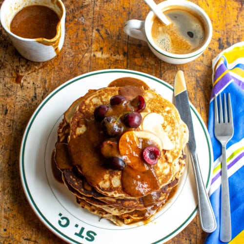 A tall stack of pancakes on a wood table.