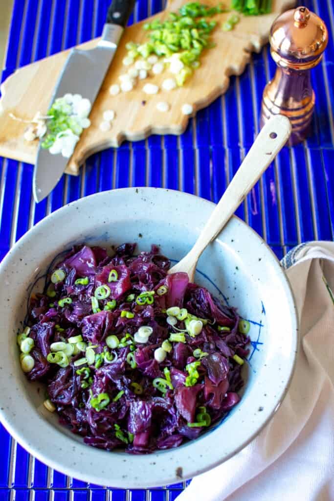 A bowl of braised red cabbage on a blue tile table .
