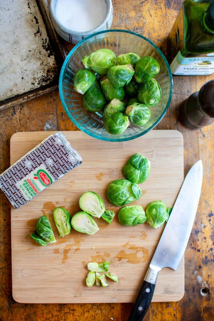 All the ingredients you need to make roasted Brussels sprouts including Brussel sprouts, olive oil, and cheese.