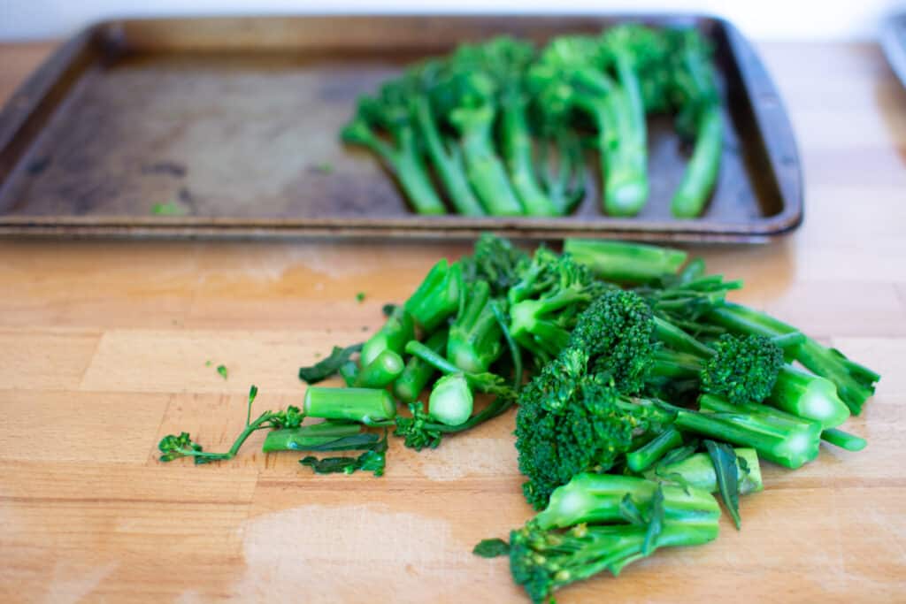 A few pieces of broccolini on a wood counter that have been cut