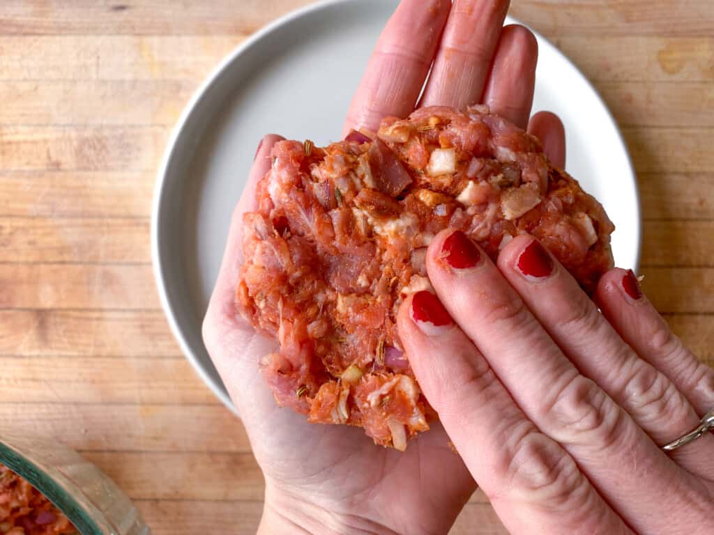 A hand forming a pork patty. 