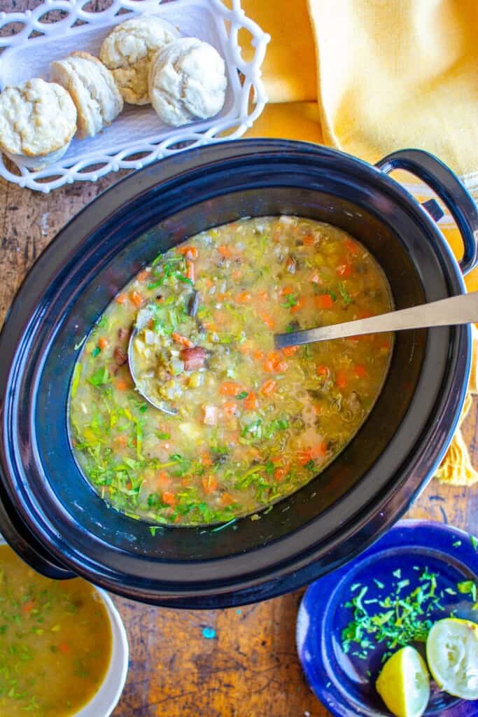 A crock pot of split pea soup with a ladle in it. 
