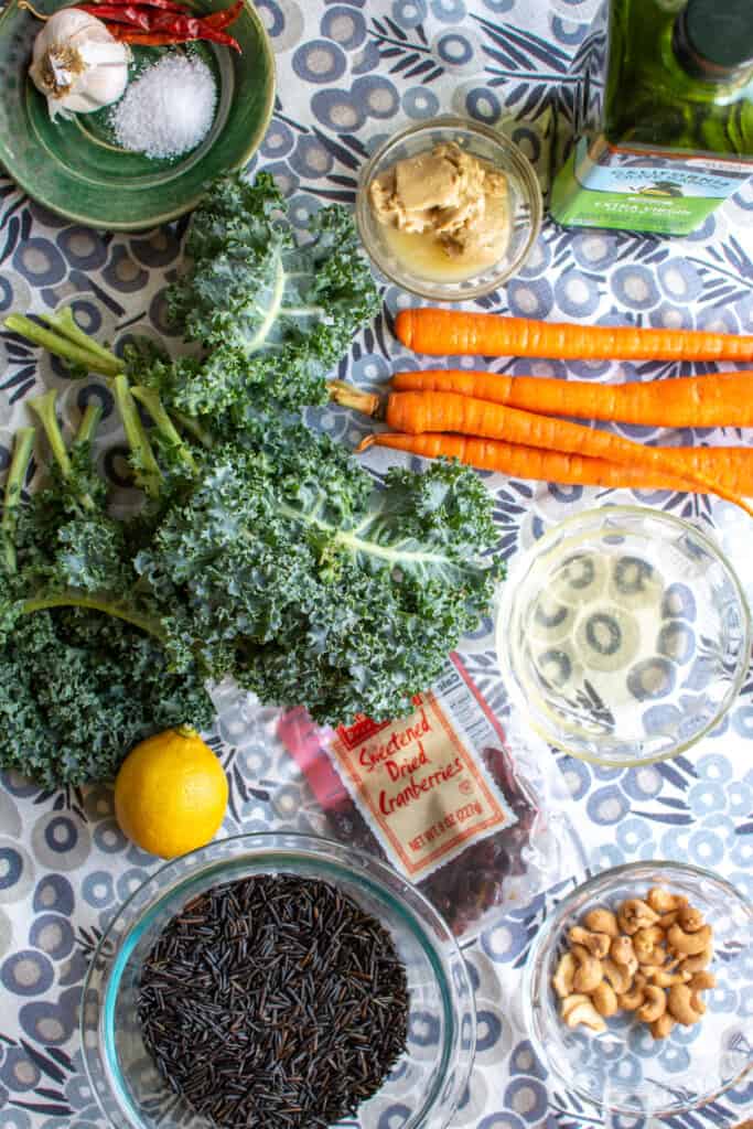 All the ingredients to make this wild rice recipe including wild rice, cashews, dried cranberries, lemon, kale, and more. 