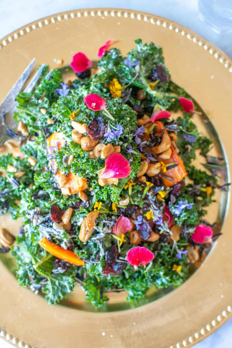 A kale salad with wild rice and carrots on a gold plate.