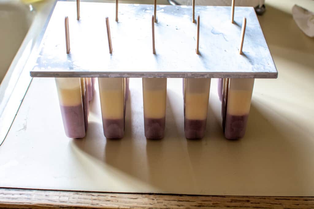 A popsicle mold filled about halfway with blueberry mixture and peach mixture. 