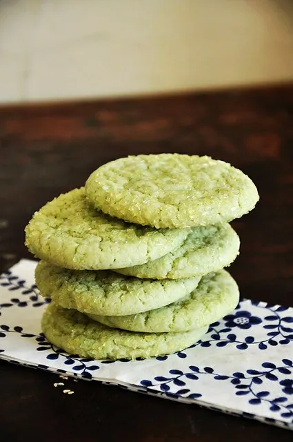 A stack of lime sugar cookies on a blue and white cloth.