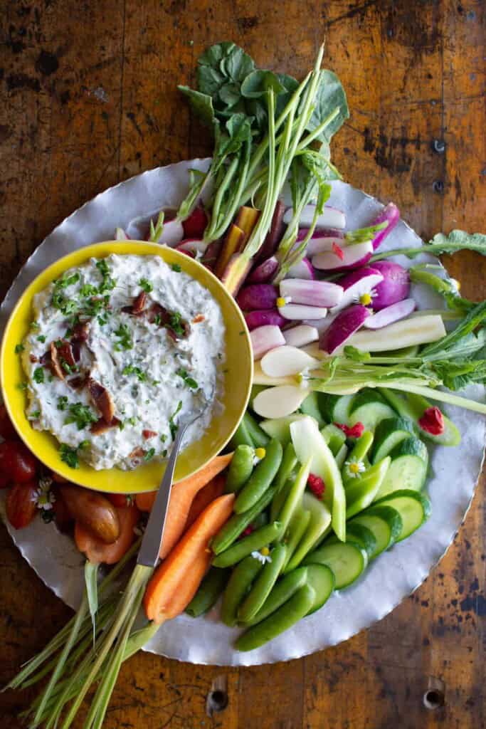 a platter of fresh vegetables with bacon dip