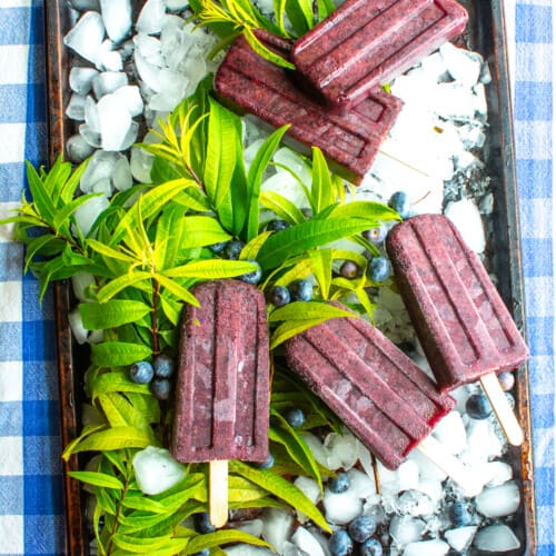 A bunch of blueberry popsicles on a baking sheet.