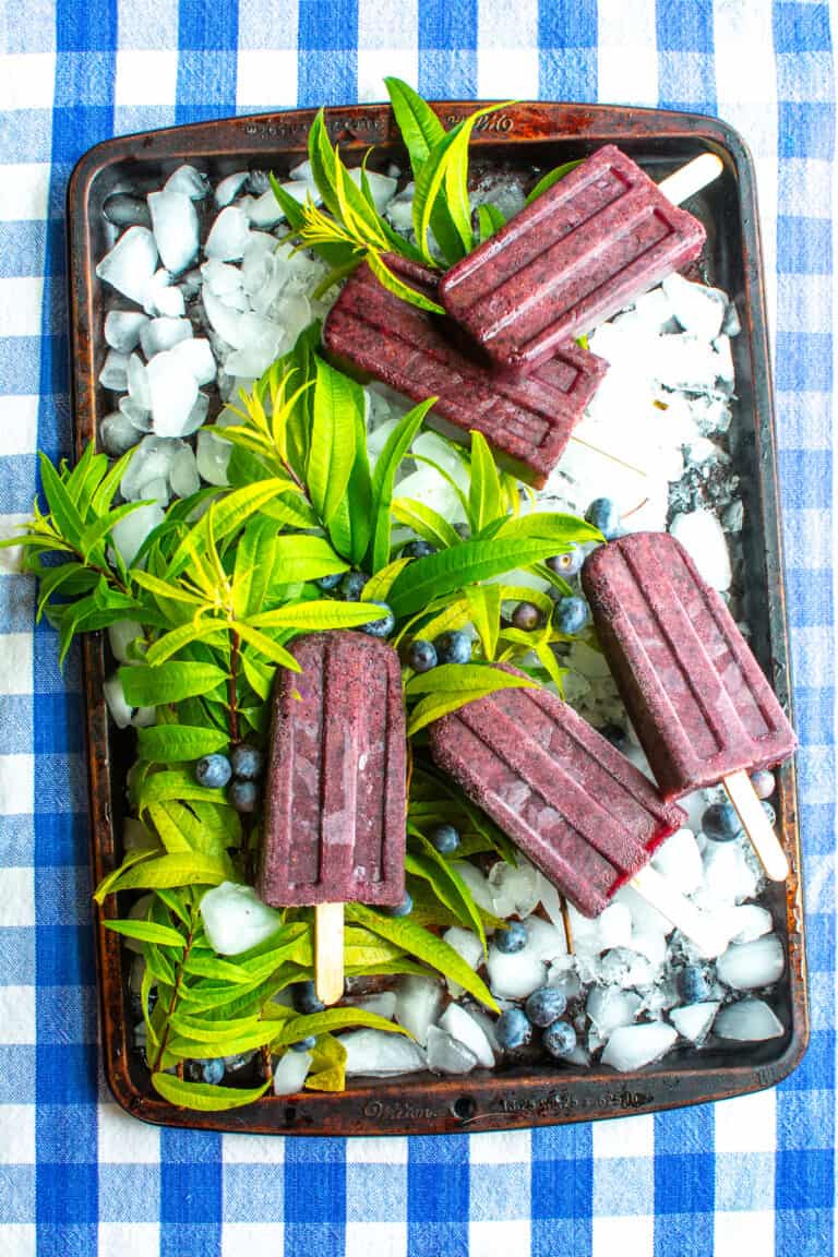 A bunch of blueberry popsicles on a baking sheet.