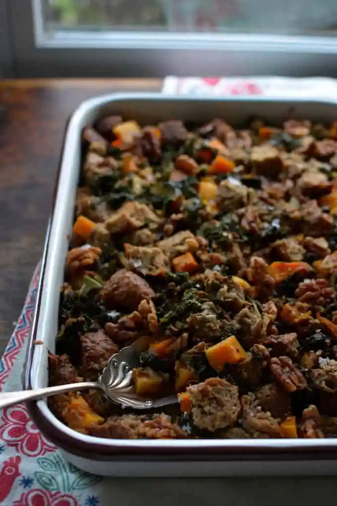 A baking dish full of stuffing with a spoon in the dish. 