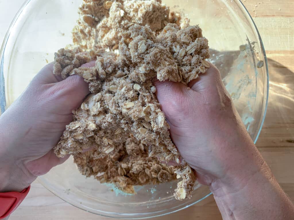 Hands mixing crumble topping