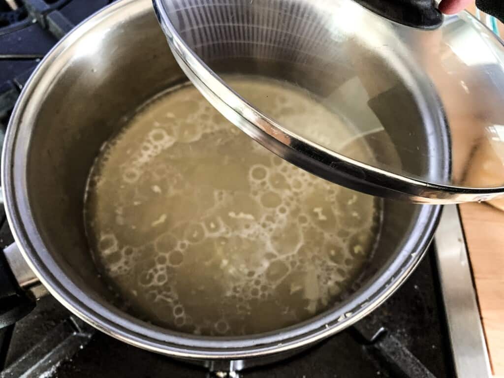 a large saucepan with garlic, broth, and salt in it