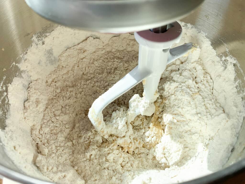 Flour being mixed into cookie dough in a stand mixer