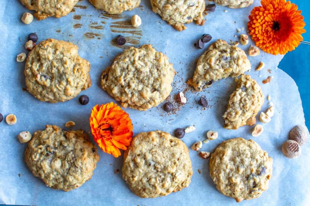 A baking sheet full of oatmeal cookies with two flowers on it. 
