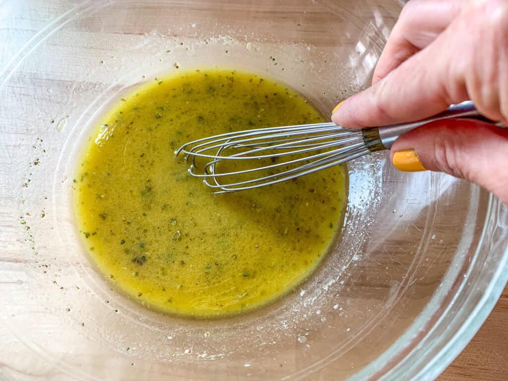 All the dressing ingredients being whisked in a glass bowl. 