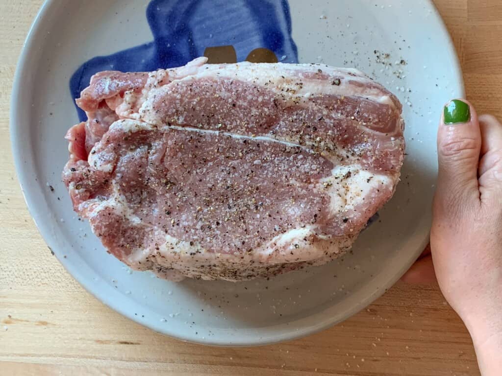 A pork shoulder roast seasoned with salt and pepper. 
