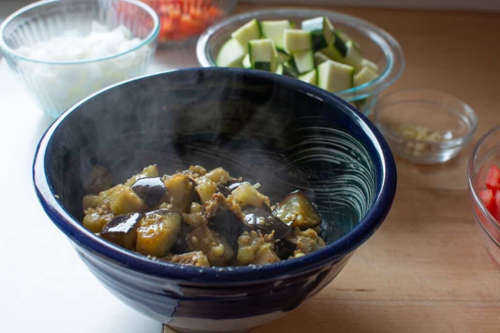 A bowl of fried eggplant sitting on a wood counter. 