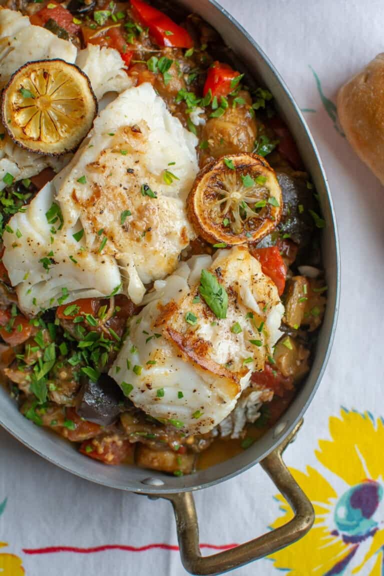 panfried cod with ratatouille on a white tablecloth with flowers