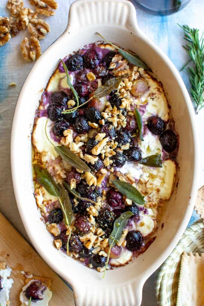 An overhead image of baked goat cheese dip with grapes and walnuts. 