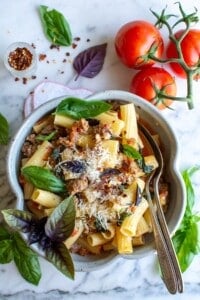 A bowl filled with rigatoni pasta with sausage and tomatoes.