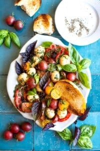 A platter of tomato basil salad on a blue tiled background