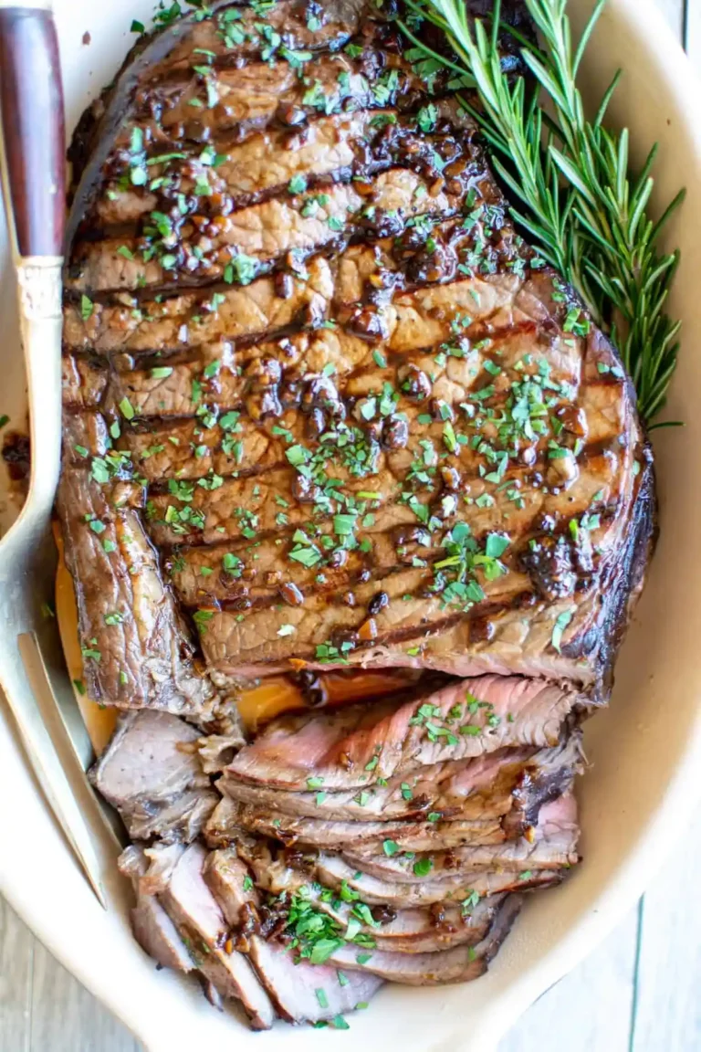 A London broil on a dish with a few pieces sliced and a fork on the side.