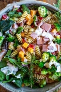 A bowl of ham and broccoli pasta salad with creamy dressing on top.