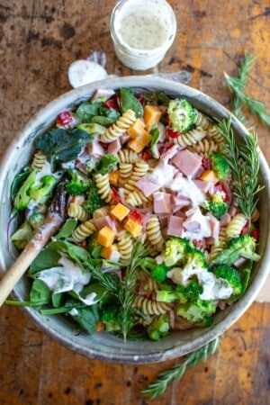 A bowl of ham and broccoli pasta salad with a spoon in the bowl.