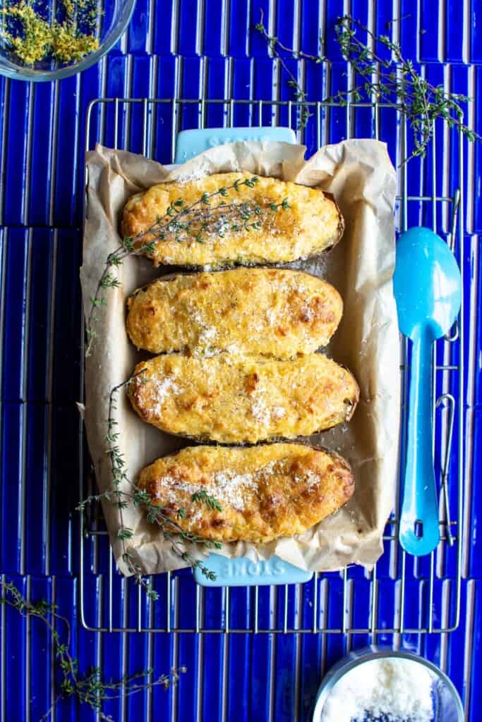 Twice baked potatoes in a blue baking dish on dark blue tile tables.