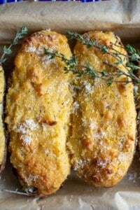 Two twice baked potatoes topped with fresh thyme leaves.