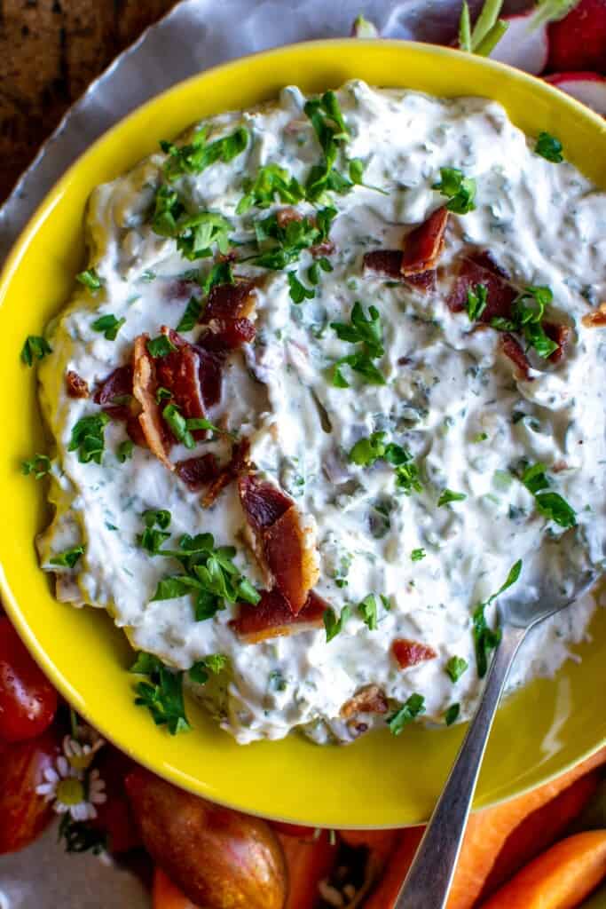 A close up of bacon blue cheese dip with a spoon in the bowl . 