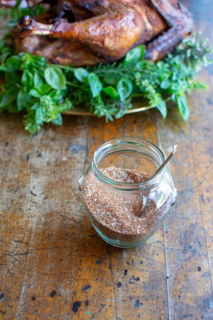 A jar of spice rub next to the smoked turkey