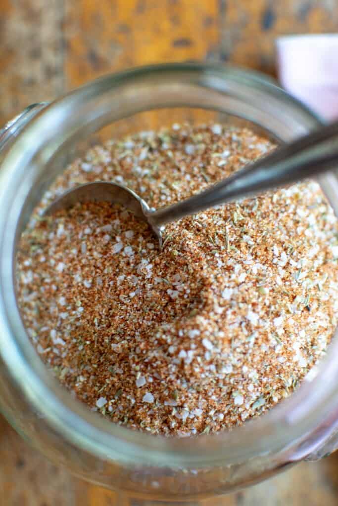 A close up of a jar of spice rub with a spoon in the jar