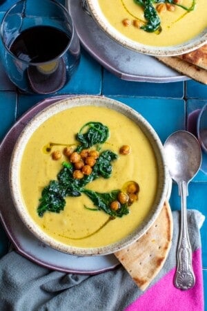 Two bowls of butternut squash soup on a blue tile table.