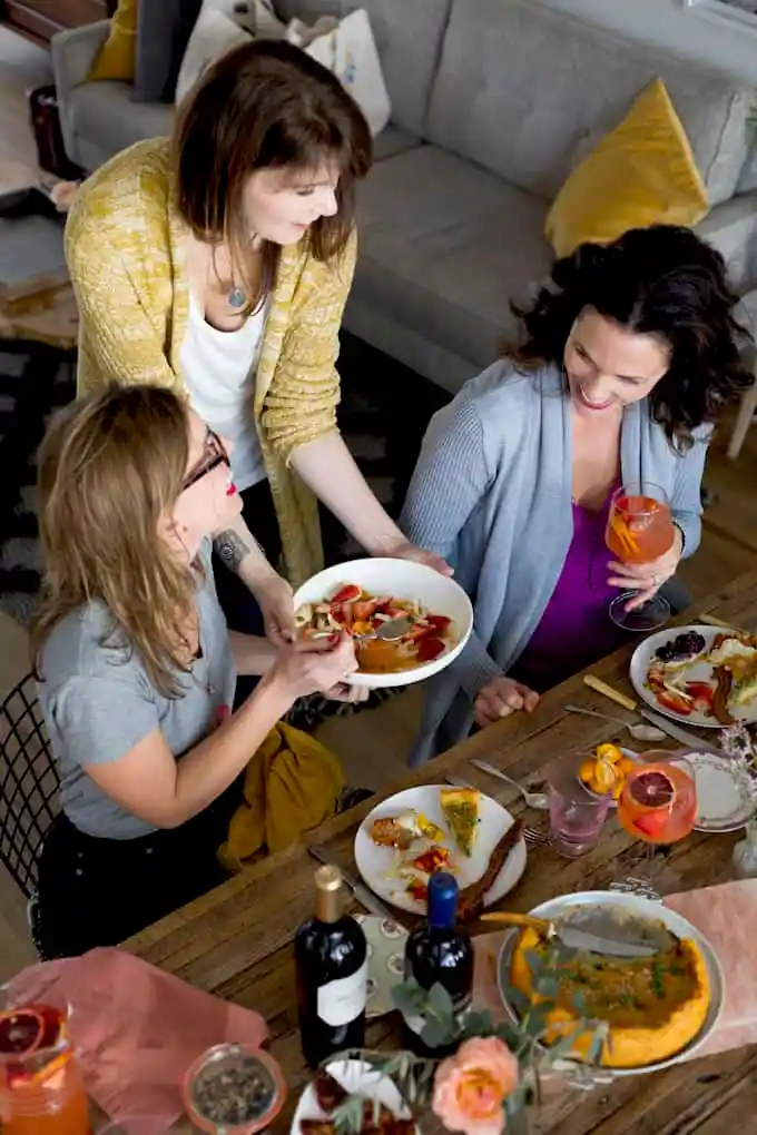 Three women enjoying Easter brunch around a wood table.