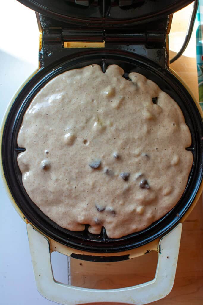 A waffle iron with wet batter in it getting ready to be cooked. 