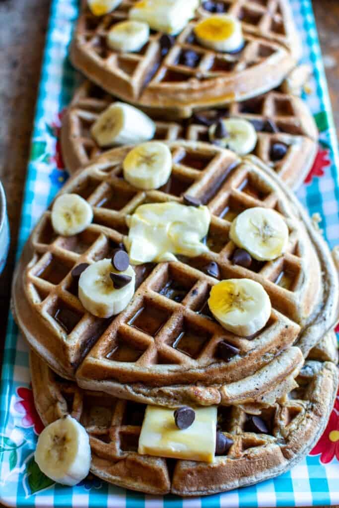 Several waffles on a blue tray with sliced bananas on top