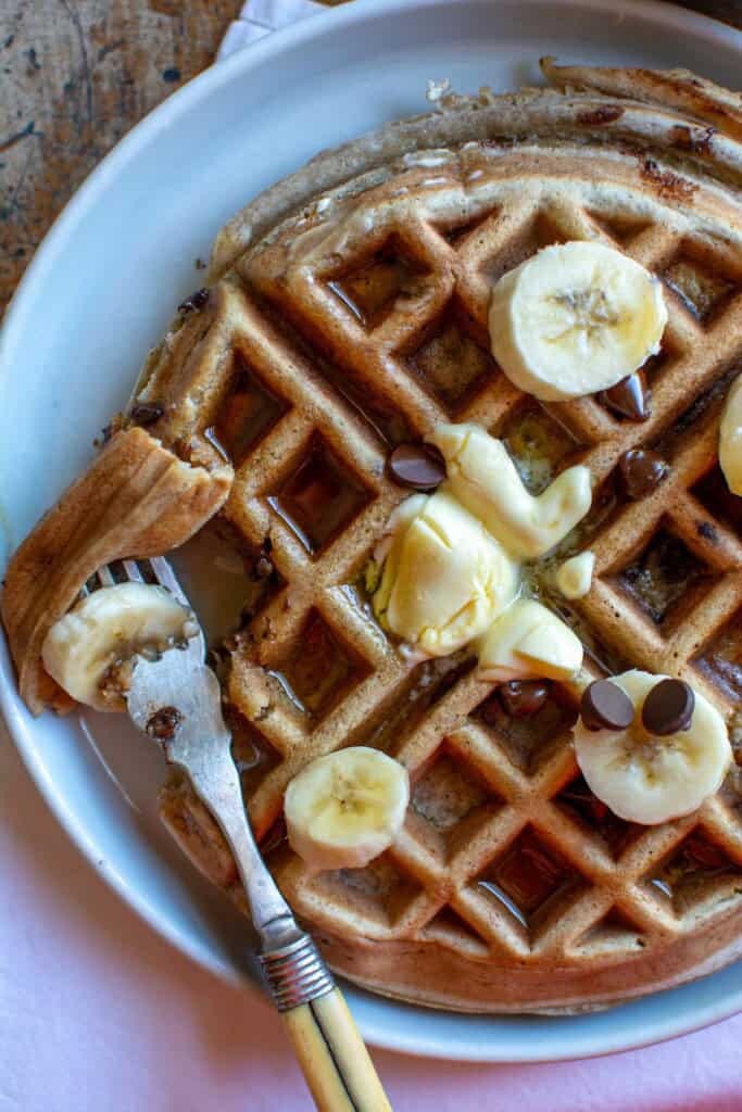 A waffle on a plate with a bite taken out of it 