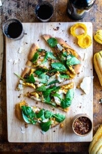 The pizza on a cutting board with a glass of wine next to it.